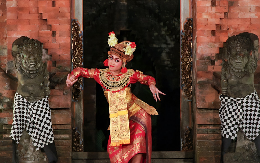 Dancer performing Ramayana Ballet at Arma Museum Resort, flanked by traditional statues.