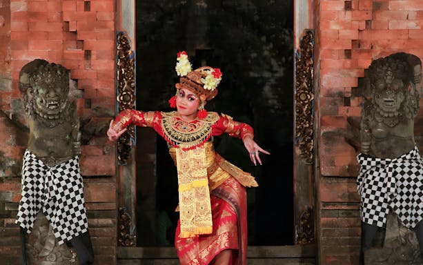 Dancer performing Ramayana Ballet at Arma Museum Resort, flanked by traditional statues.