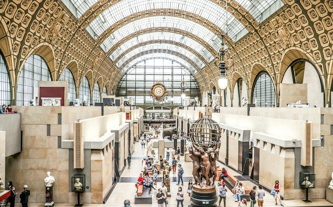 Orsay Museum interior with sculptures and visitors at a temporary exhibition in Paris.