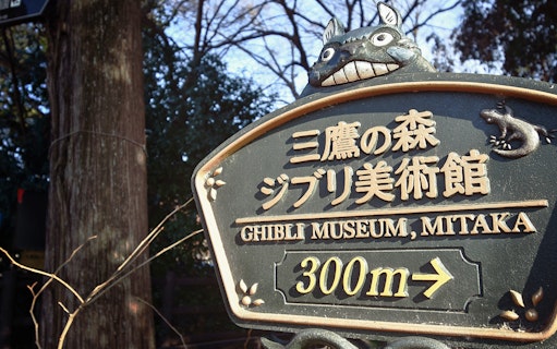 Sign for Ghibli Museum in Mitaka with Totoro figure on top.