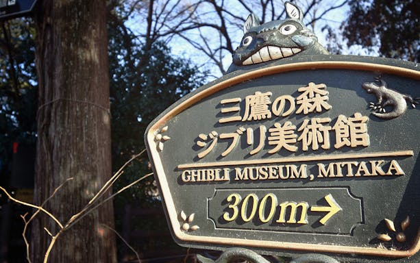 Sign for Ghibli Museum in Mitaka with Totoro figure on top.