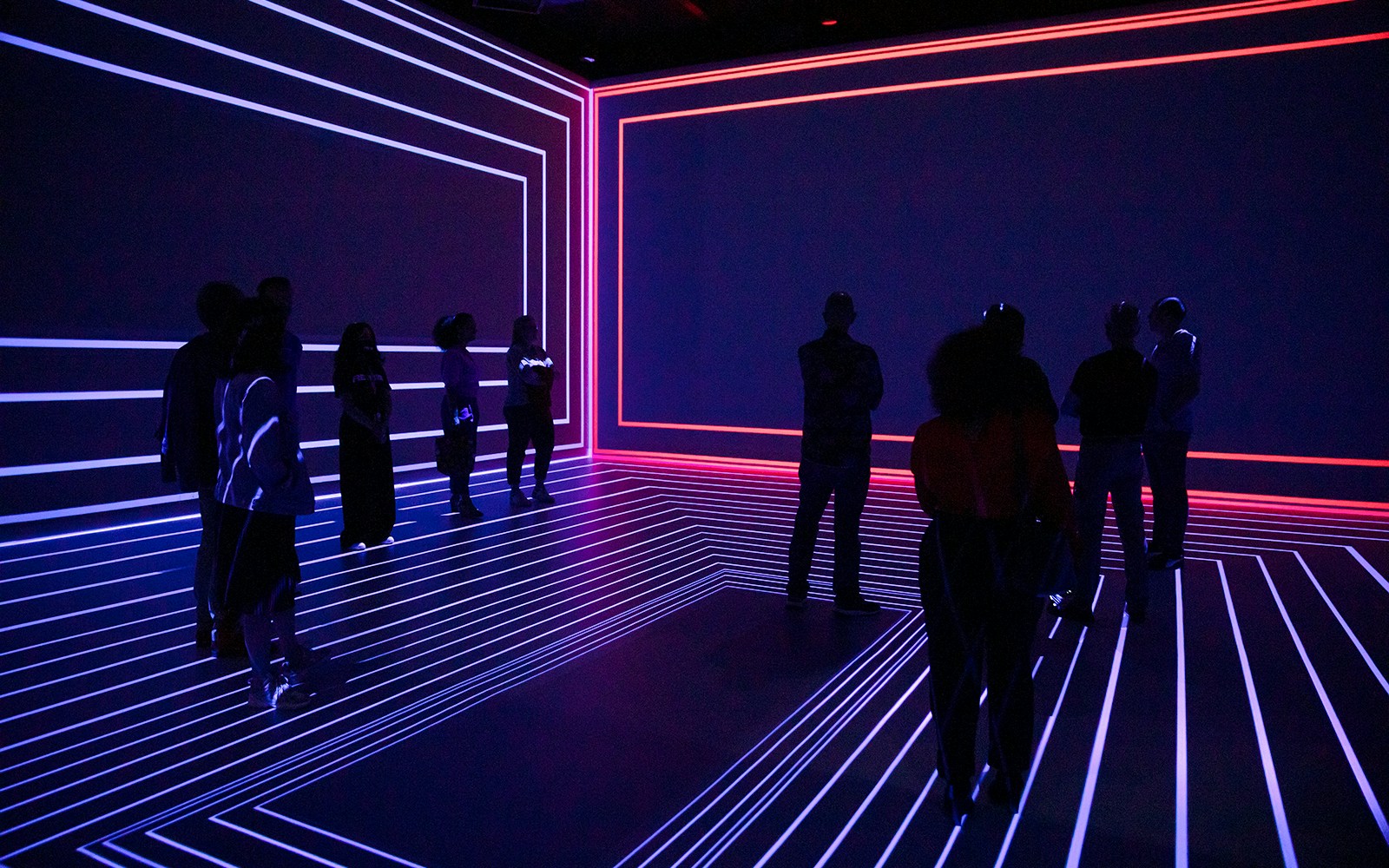 Guests exploring the Remastered audiovisual experience in Rotterdam with neon light patterns.