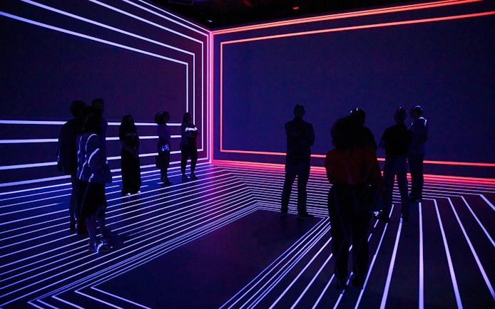 Guests exploring the Remastered audiovisual experience in Rotterdam with neon light patterns.
