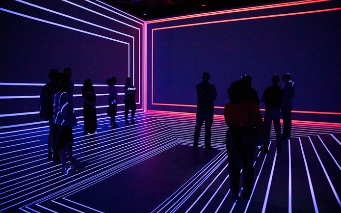 Guests exploring the Remastered audiovisual experience in Rotterdam with neon light patterns.