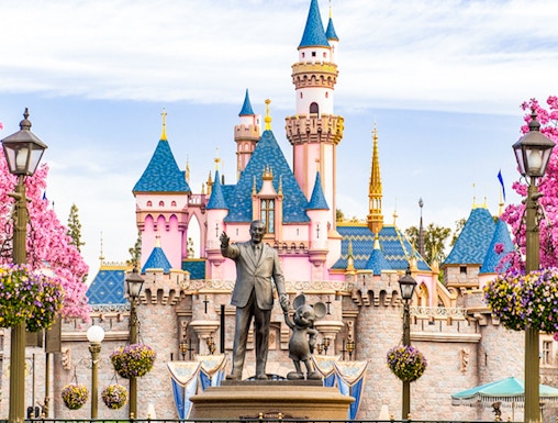 Disneyland California castle with cherry blossoms and blue sky.