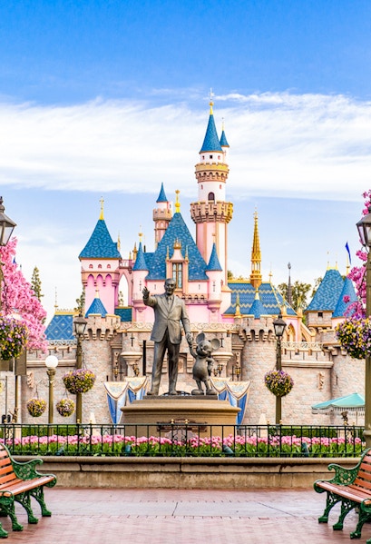 Disneyland California castle with cherry blossoms and blue sky.