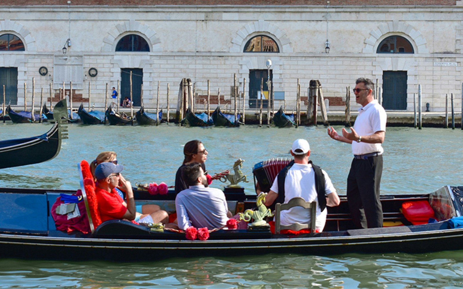 Gondola ride with serenade on Venice canal, featuring a musician and tourists.