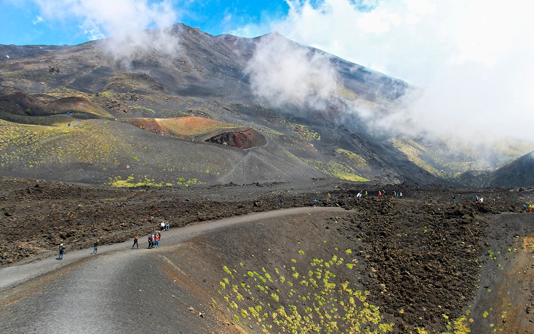 Visitors trekking near Mount Etna's summit on a guided tour.