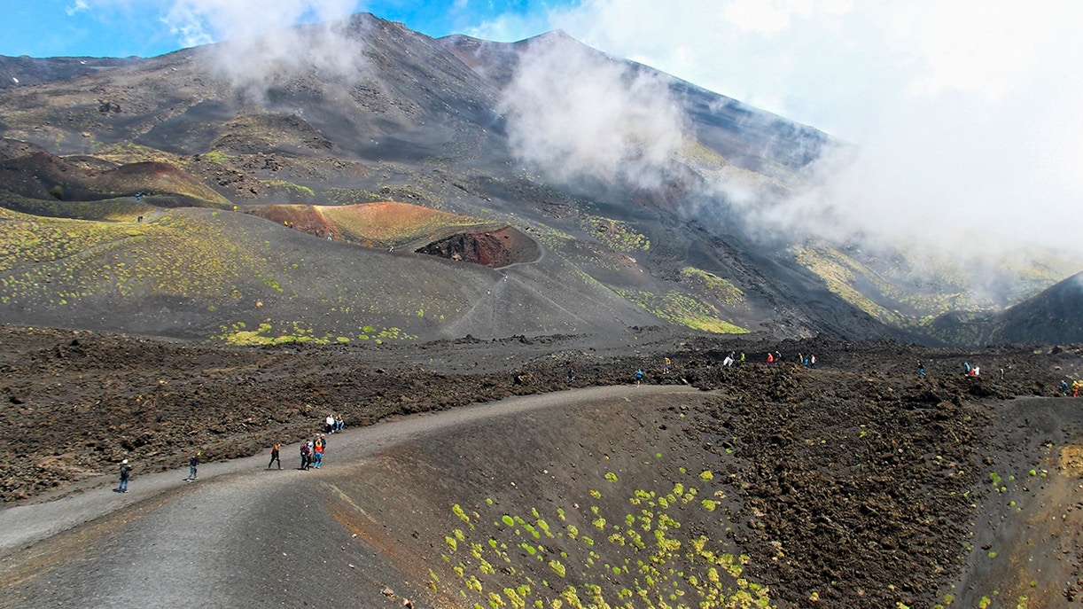 Visitors trekking near Mount Etna's summit on a guided tour.