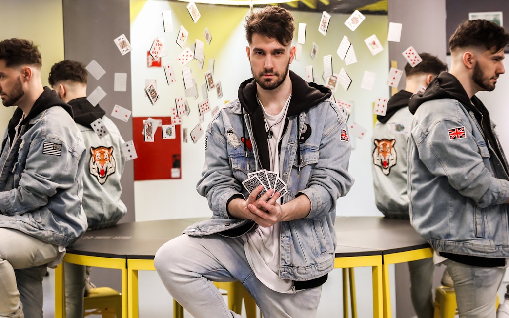 Man holding playing cards with reflections and floating cards at Museum of Illusions.