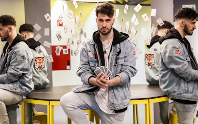 Man holding playing cards with reflections and floating cards at Museum of Illusions.