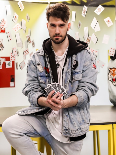 Man holding playing cards with reflections and floating cards at Museum of Illusions.