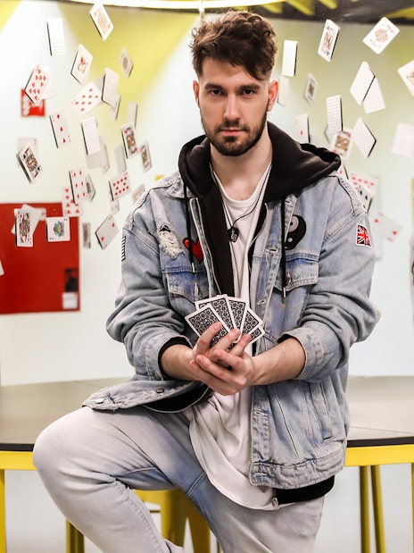 Man holding playing cards with reflections and floating cards at Museum of Illusions.