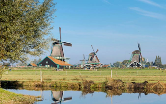 Windmills at Zaanse Schans, Netherlands, with a reflection in a canal.
