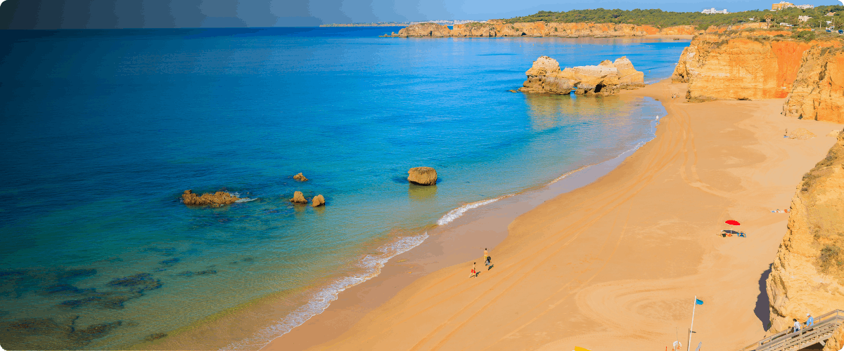 Golden beach with cliffs and clear blue water in Portimão, Portugal.