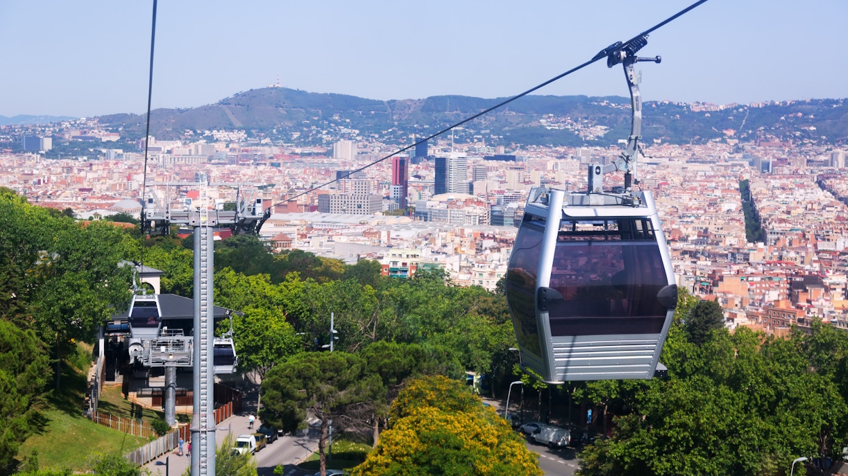Montjuic Cable Car ascending over Barcelona cityscape with views of the Mediterranean Sea.