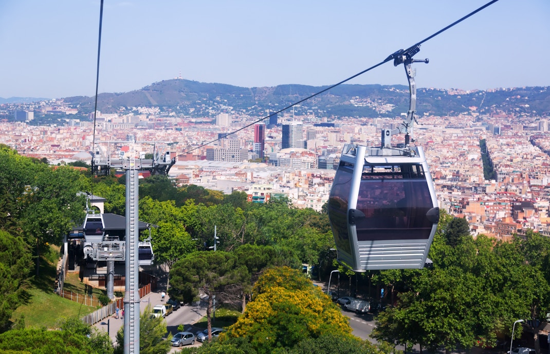 Montjuic Cable Car ascending over Barcelona cityscape with views of the Mediterranean Sea.