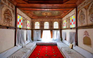 Interior of Gjirokastra Castle with colorful stained glass windows and ornate wooden ceiling.