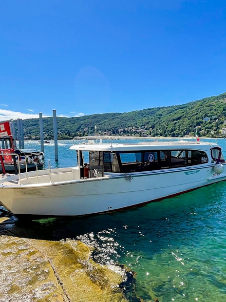 Boat docked at Isole Borromee for Hop-on Hop-off tour, with scenic lake and hills in background.