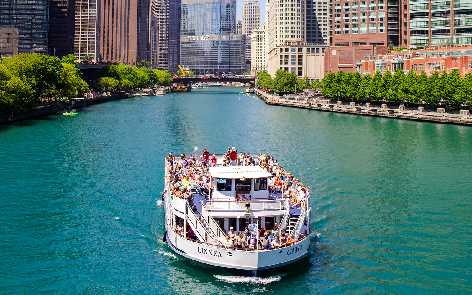 Tour boat on Chicago River with city skyline in background.