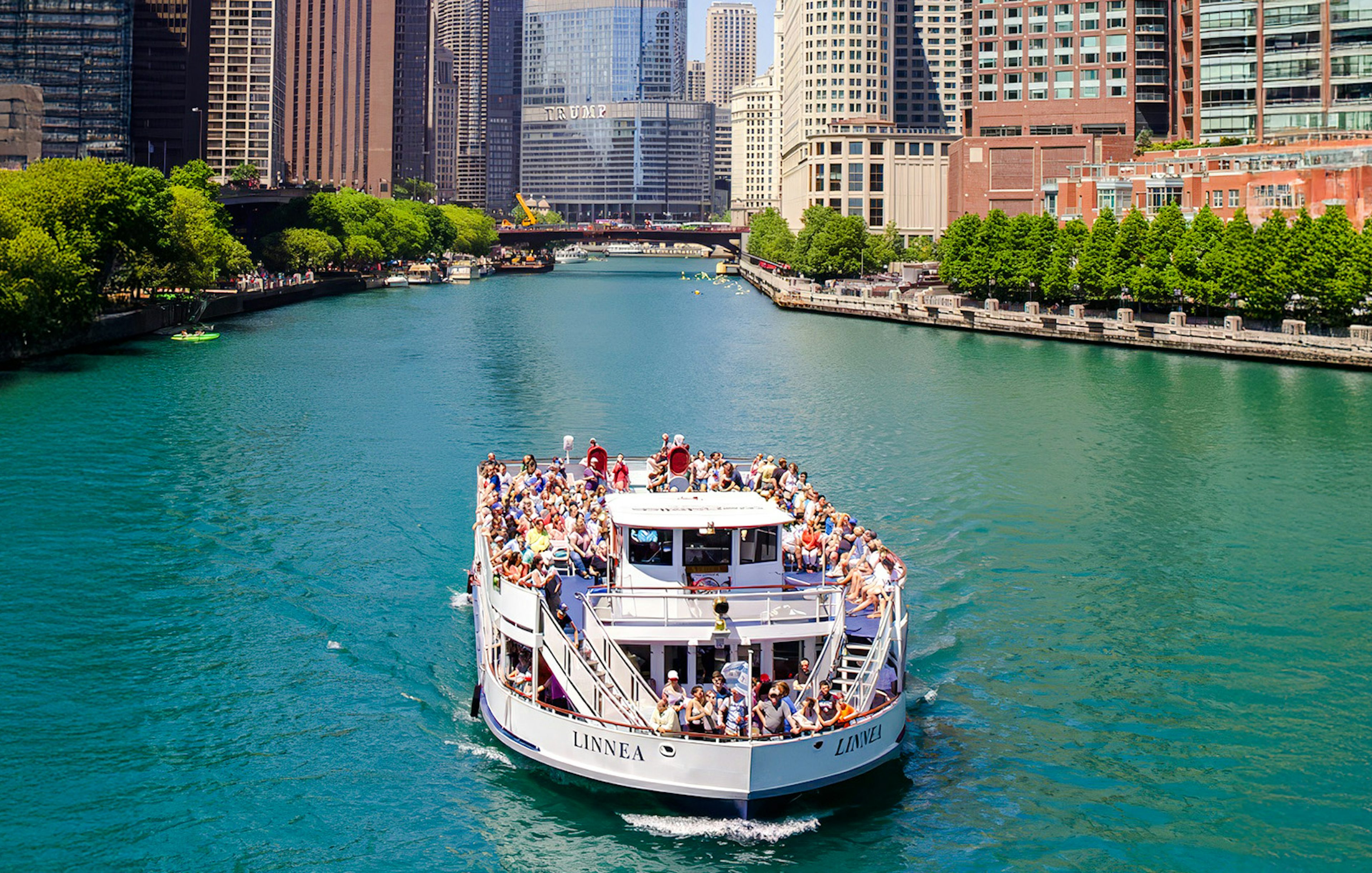Tour boat on Chicago River with city skyline in background.