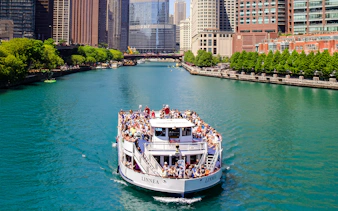Tour boat on Chicago River with city skyline in background.