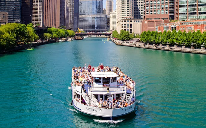 Tour boat on Chicago River with city skyline in background.