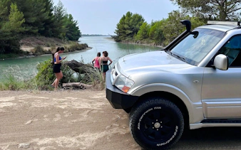 4X4 Jeep parked by Karavasta Lagoon with tourists exploring the scenic waterway.