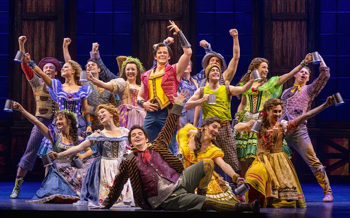 Cast performing a lively tavern scene from Beauty and the Beast musical.