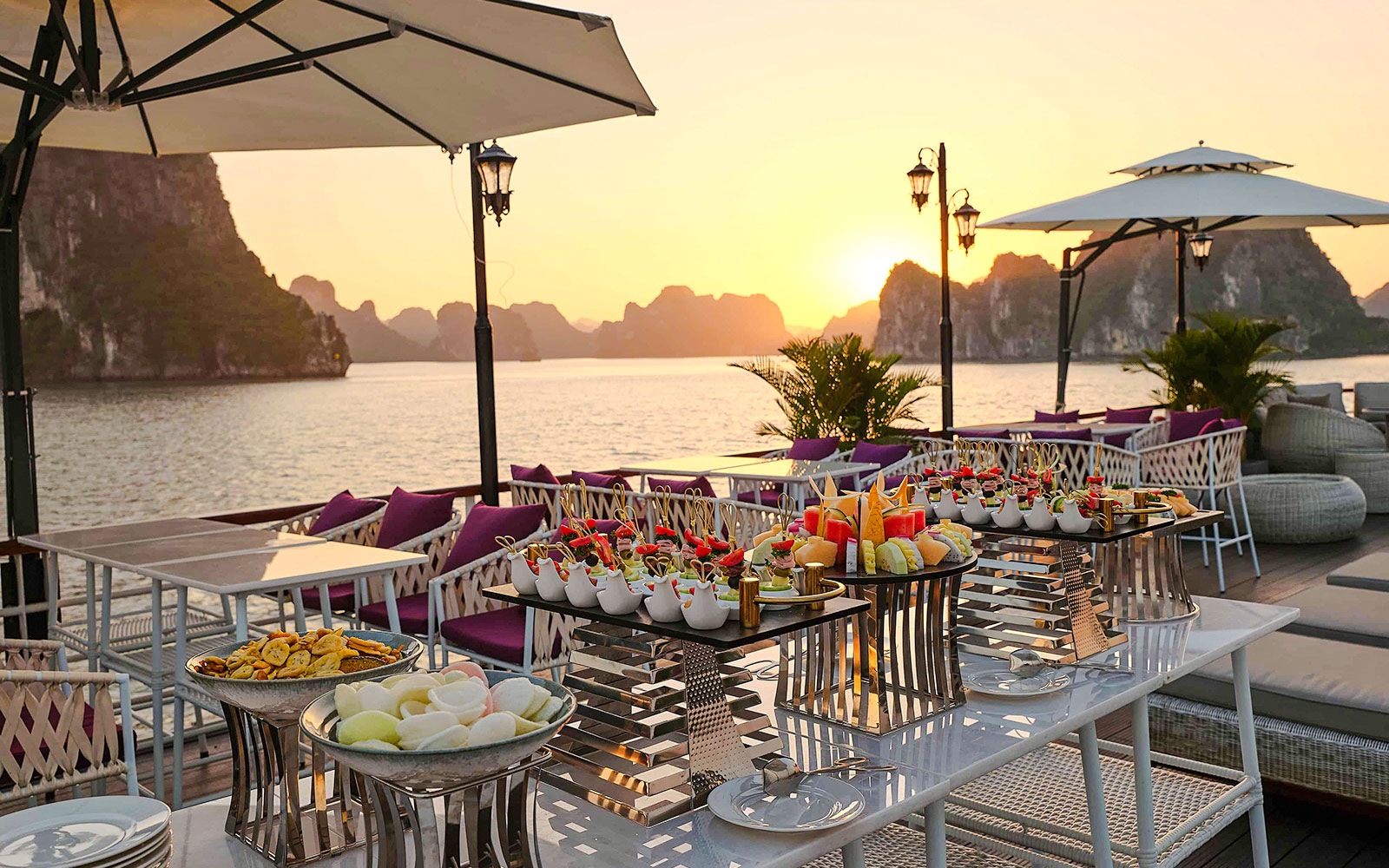 Outdoor dining setup on a 5-Star Irish Cruise in Ha Long Bay at sunset.