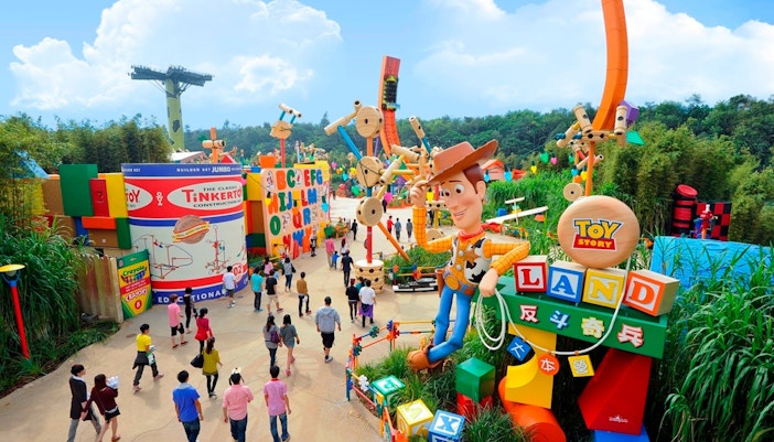 Visitors walking through Toy Story Land with giant Woody statue, Disneyland Hong Kong.