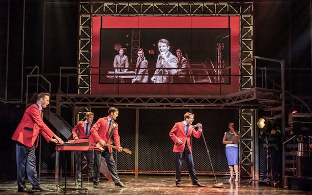 Performers in red jackets on stage during a Jersey Boys musical scene.