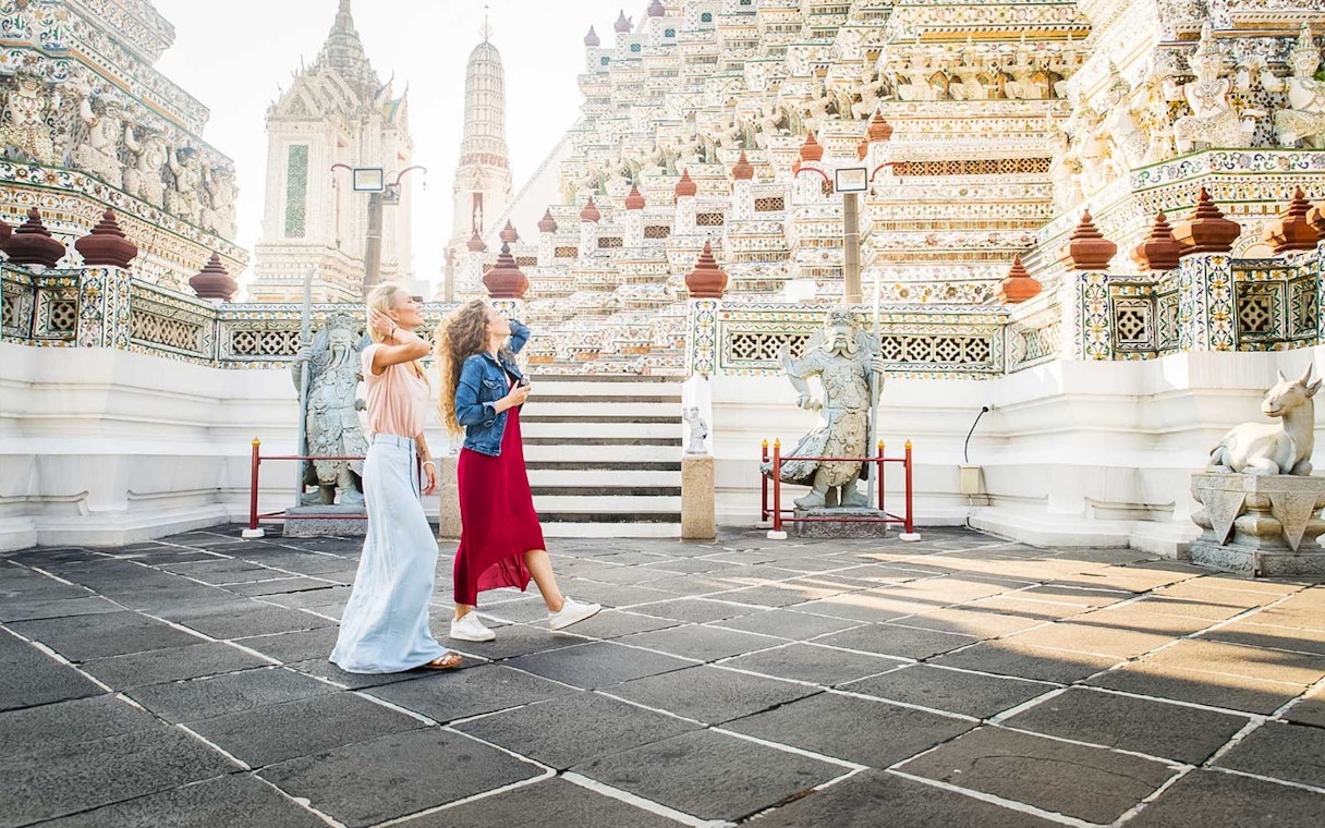 Visitors exploring ornate temple architecture at Grand Palace, Bangkok.