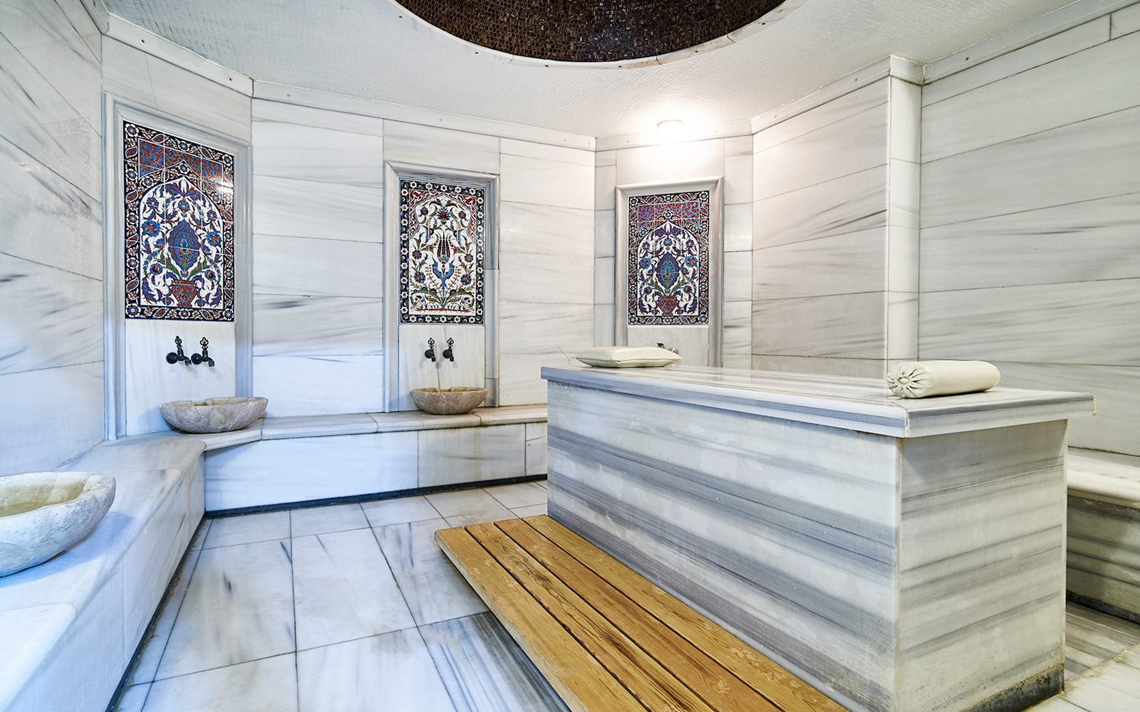 Sifa Hamam interior with marble benches and decorative tiles.