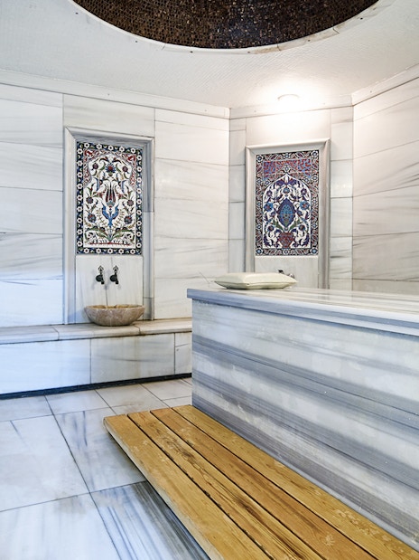 Sifa Hamam interior with marble benches and decorative tiles.
