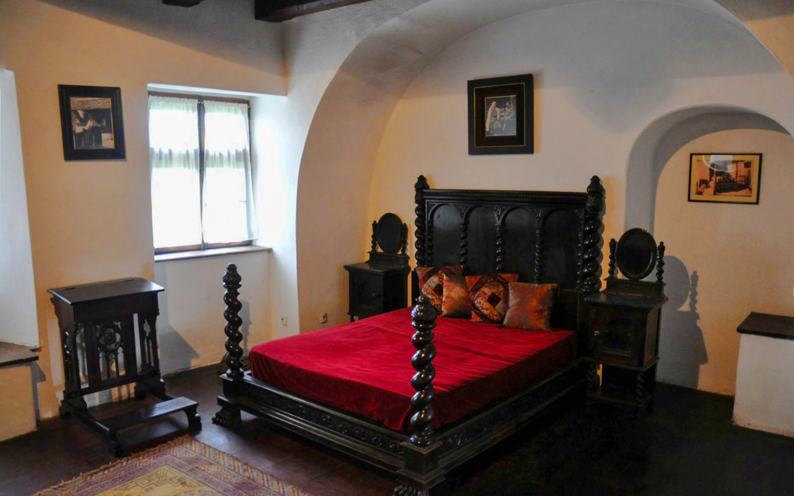 Bran Castle bedroom with ornate wooden bed and red bedding.