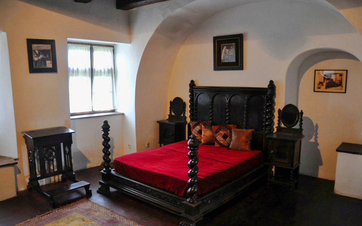Bran Castle bedroom with ornate wooden bed and red bedding.