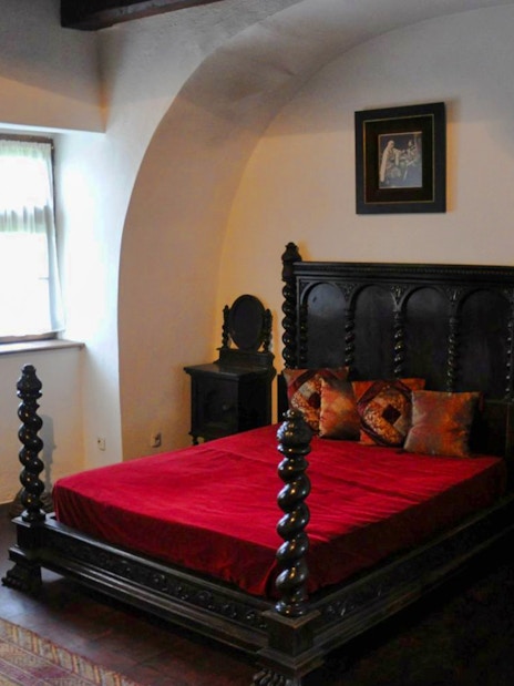 Bran Castle bedroom with ornate wooden bed and red bedding.