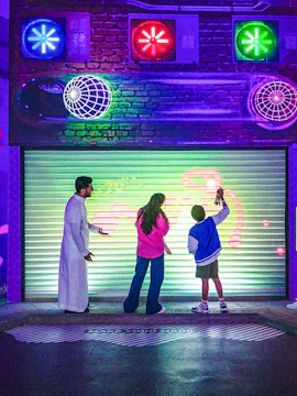 Visitors interacting with a digital wall at House of Hype, featuring colorful neon lights.
