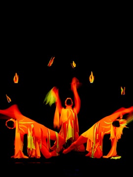 Performers in vibrant costumes at Black Light Theatre, Prague, creating dynamic visual effects.