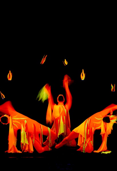 Performers in vibrant costumes at Black Light Theatre, Prague, creating dynamic visual effects.