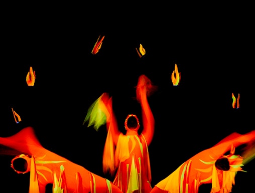 Performers in vibrant costumes at Black Light Theatre, Prague, creating dynamic visual effects.