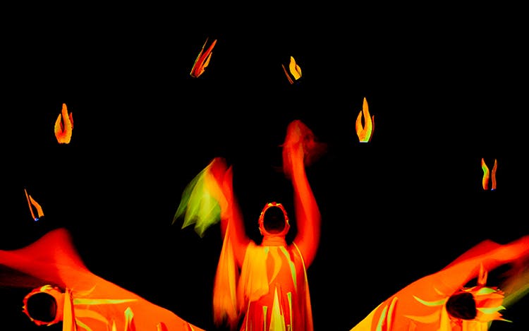 Performers in vibrant costumes at Black Light Theatre, Prague, creating dynamic visual effects.