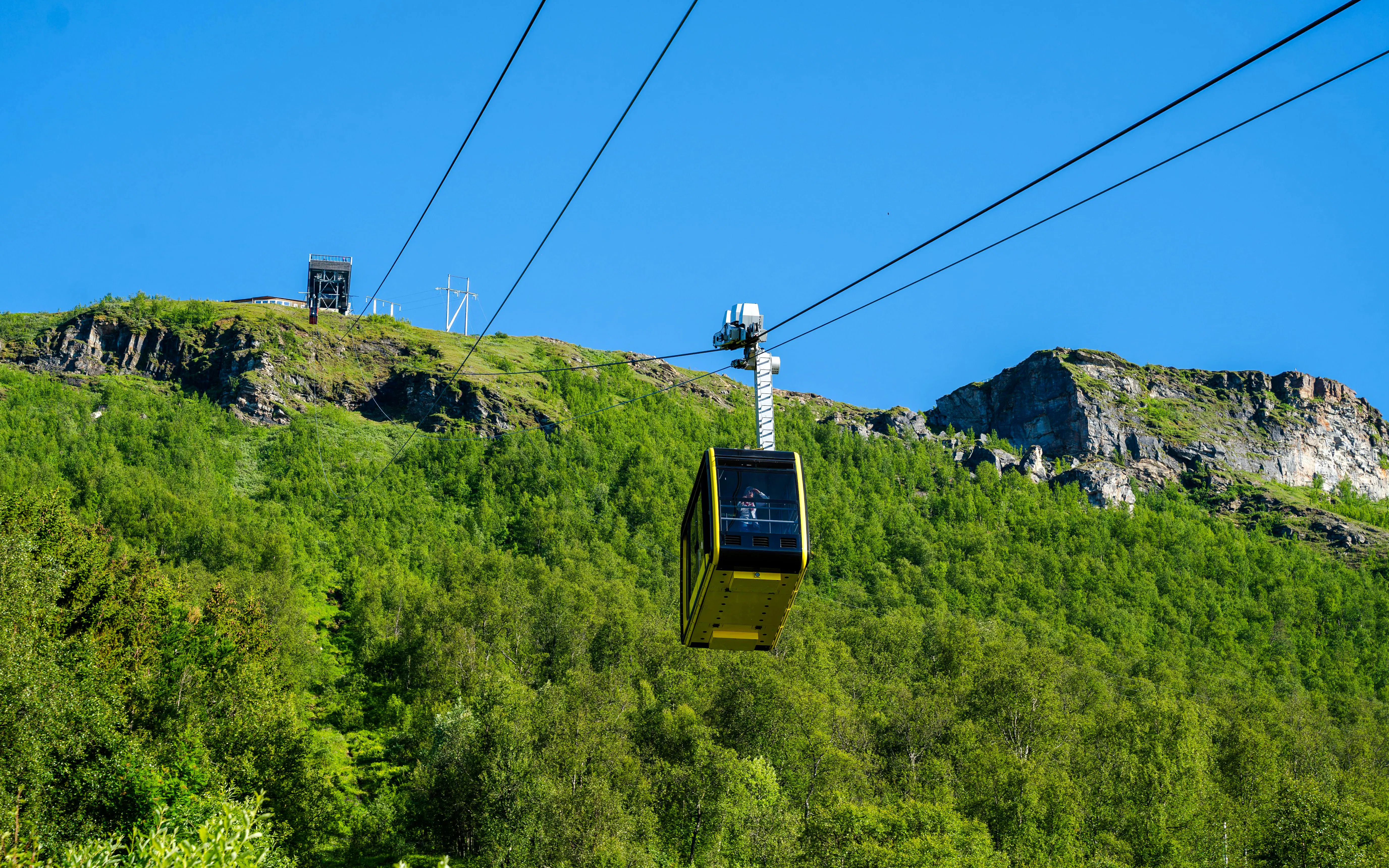 Fjellheisen cable car ascending over green hills in Tromso, Norway.