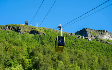 Fjellheisen cable car ascending over green hills in Tromso, Norway.