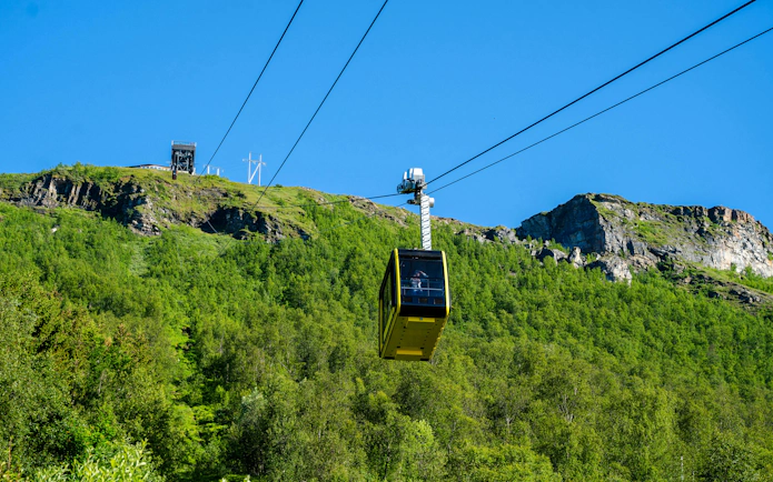 Fjellheisen cable car ascending over green hills in Tromso, Norway.