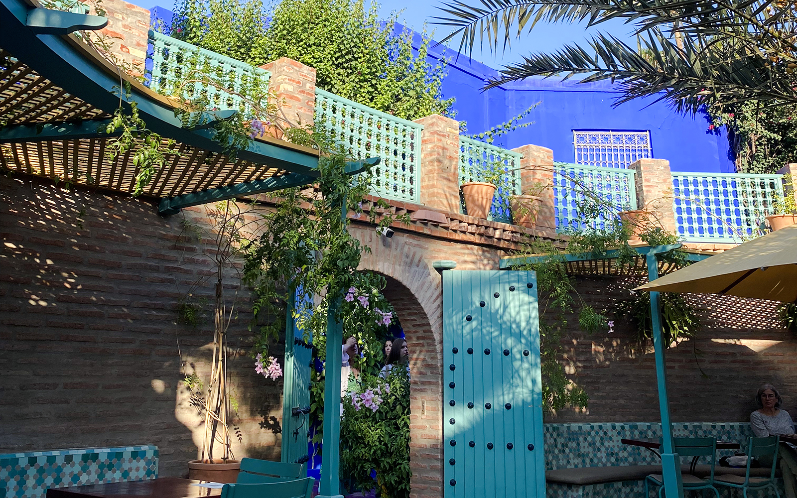 Jardin Majorelle courtyard with blue doors, brick walls, and lush greenery.