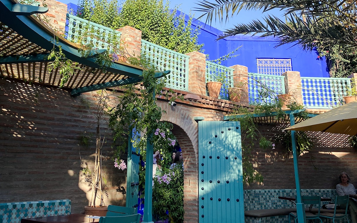 Jardin Majorelle courtyard with blue doors, brick walls, and lush greenery.