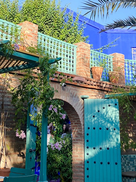 Jardin Majorelle courtyard with blue doors, brick walls, and lush greenery.