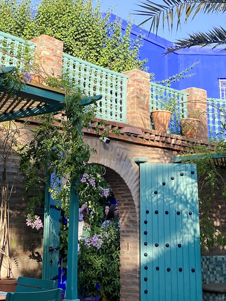 Jardin Majorelle courtyard with blue doors, brick walls, and lush greenery.